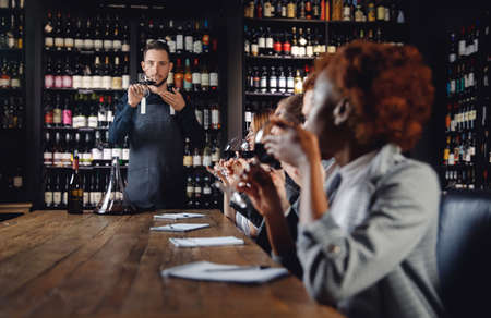 Tasting red wine Professional sommeliers man and woman and taking notes at degustation notepadの写真素材