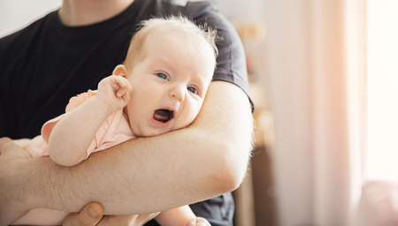 Young Father man tries to calm crying and toddler tantrum of baby girl. Concept stress parenting childの写真素材