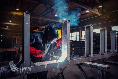 Factory industry worker welder in protective uniform with mask on workplace metalwork