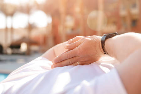 Closeup hand of caucasian young man sitting and meditating in lotus pose background palms sunsetの写真素材