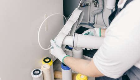 Plumber working install new cartridge for cold water filter in white kitchenの写真素材