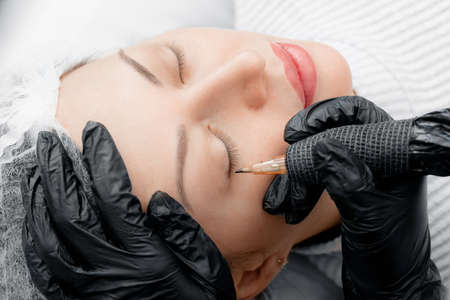 Permanent tattoo makeup on eyelashes of eyes of face young woman in beauty salon, top viewの写真素材