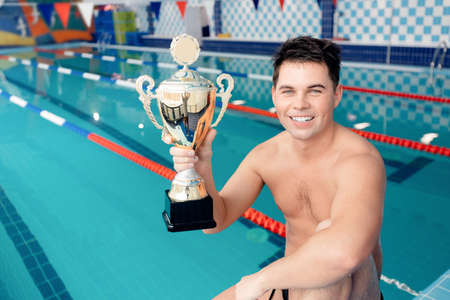 Concept swimming competition, happy young man winner swimmer holding trophyの写真素材