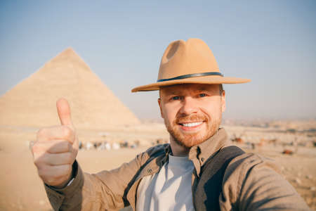 Travel selfie photo tourist man in hat background pyramid of Egyptian Giza, sunset Cairo, Egyptの写真素材