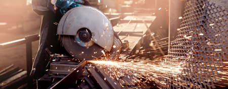 Banner Industry worker working electric wheel grinding on steel structure in factory, light sparkの写真素材