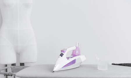 White iron steamer for ironing clothes stands on board at workplace of seamstress tailorの写真素材