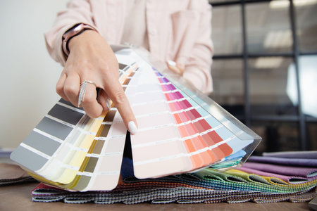Closeup hand of woman decorator interior designer is choosing catalogue colors ral for projectの写真素材