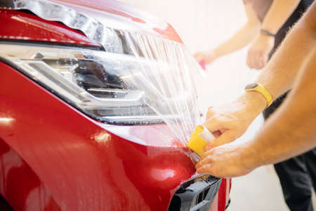 Closeup paint protection PPF is vinyl film, master installation on hood modern luxury carの写真素材
