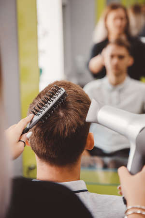 Master woman barber does hairstyle and styling with dryer hair to guy barbershopの写真素材