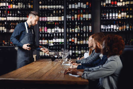 Sommelier pouring red wine into carafe decanter to make aeration drinkの写真素材