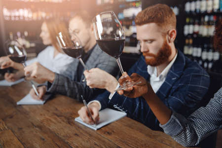 Closeup tasting red wine sommeliers and taking notes at degustation notepadの写真素材