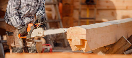 Carpenter worker with chainsaw log wooden. Woodwork job, house frame buildingの写真素材
