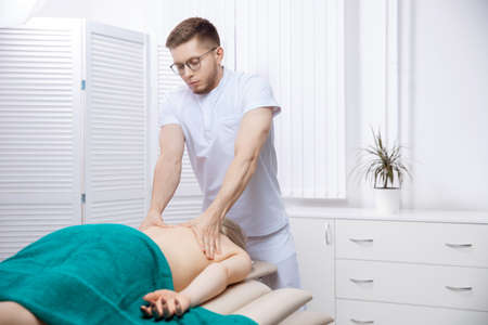 Concept physiotherapy massage for rehab sport injury athlete back. Doctor osteopath use therapy for woman in clinicの写真素材