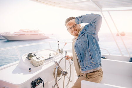 Business portrait of young successful man driving yacht on sunny day