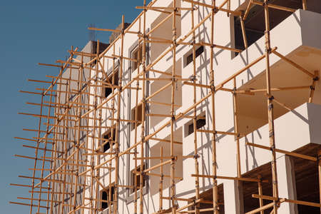 Construction building houses made of stone and sandstone using scaffolding in Egypt, blue skyの写真素材