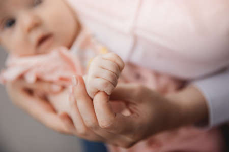 Mother with newborn baby hold hands closeup. Concept love and support of kidの写真素材