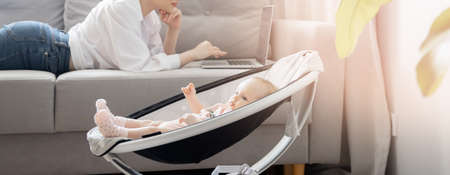 Baby lies in automatic carrycot, sunlight at homeの写真素材