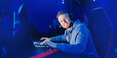Portrait happy young man streamer professional gamer of online games with headphones, neon color bannerの写真素材