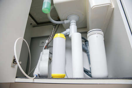 Installing water filter filtration in house in white kitchenの写真素材