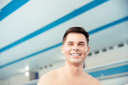 Portrait young man smiling on background of pool, concept of swimmer before training at schoolの写真素材