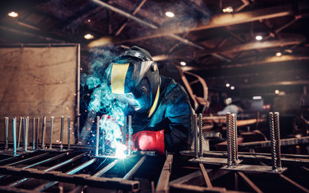 Factory industrial weld worker in workplace with spark. Professional welder erecting metal steel