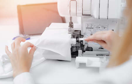 Concept Online tailor. Woman seamstress watches video lessons on tablet for sewing pattern clothesの写真素材
