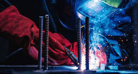 Professional welder erecting metal steel. Banner Factory industrial worker in workplace with sparkの写真素材