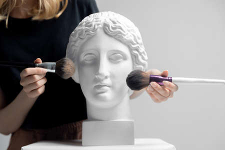 Makeup artist young woman uses brush to apply powderの写真素材