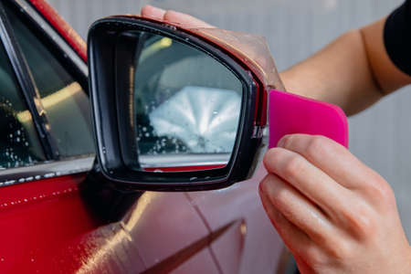 Closeup Installs vinyl film for protect paint body side mirrors red carの写真素材
