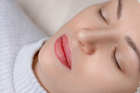 Permanent make-up of lips, eyebrows and eyes, woman on tattoo procedureの写真素材