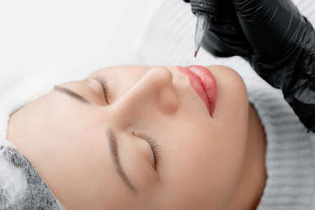 Permanent tattoo makeup on lips of face young woman in beauty salon, top viewの写真素材