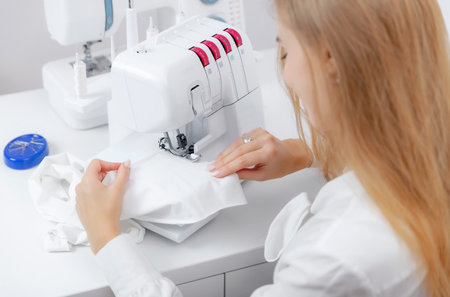 Seamstress tailor woman working on sewing machine, white background top viewの写真素材