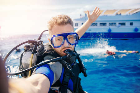 Selfie photo man diver scuba diving blue water sea looking at camera with sun light. Concept travel extreme sportの写真素材