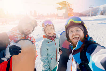 Group of friends skiing and snowboard make selfie photo in winter with sun light on ski resortの写真素材