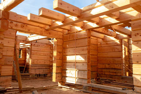 New house wooden log construction interior with exposed framing with sun lightの写真素材