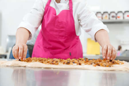 Step-by-step Easter cake, pastry chef prepares dough with raisins for festive kulichの写真素材
