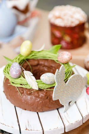 Easter cake orthodox sweet bread kulich and colorful chocolate eggs on festive tableの写真素材