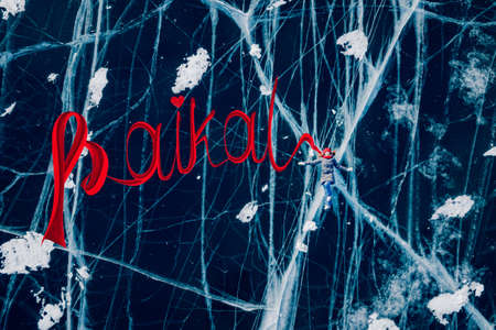 Woman tourist on ice skates and with long red scarf on frozen cracks lake Baikal, aerial top viewの写真素材
