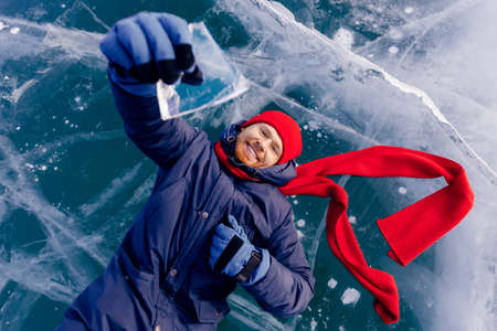 Travel winter Lake Baikal, smile man tourist in red cap lie on iceの写真素材