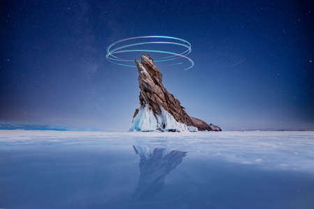 Beautiful night landscape island Ogoy winter lake Baikal with transparent cracked blue ice with starsの写真素材