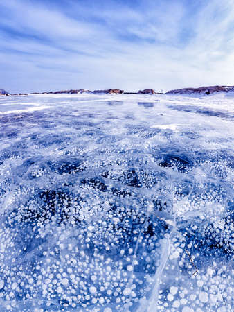 Gas methane bubbles frozen in winter ice of lake Baikal, abstract backgroundの写真素材