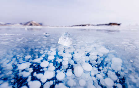 Gas methane bubbles frozen in winter ice of lake Baikal, abstract backgroundの写真素材