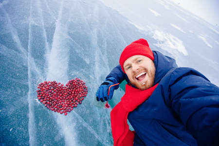 Man tourist drink cocktail winter ice kiss of Lake Baikal with cranberry heart. Concept travel Russiaの写真素材