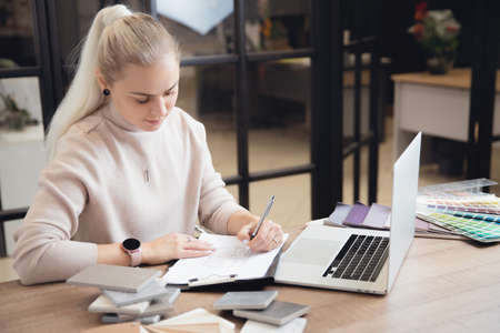 Portrait young woman professional designer develops design of apartment project in workplace laptopの写真素材