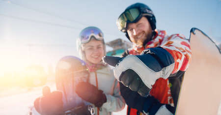 Banner winter sport travel. Happy young couple man and woman snowboarders on background of ski resort sun dayの写真素材