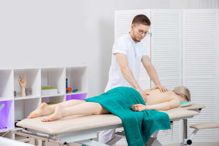 Doctor osteopath use therapy for woman in clinic. Concept physiotherapy massage for rehab sport injury athlete backの写真素材