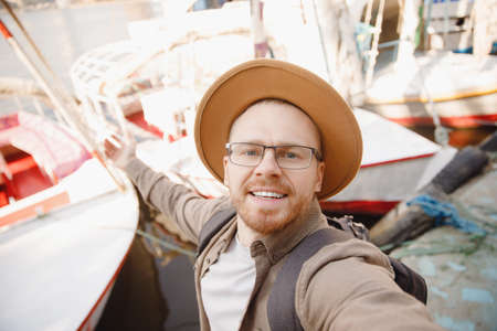 Young man driver in hat takes selfie photo background yacht summer day, concept rent for travel boatの写真素材