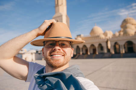 Tourist man in hat takes travel selfie photo background El Mina Masjid mosque in Hurghada, Egypt sunlightの写真素材