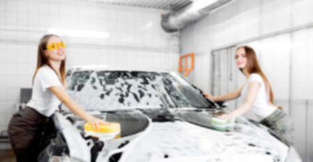 Background blurred hand hold sponge over black car for washing white foamの写真素材
