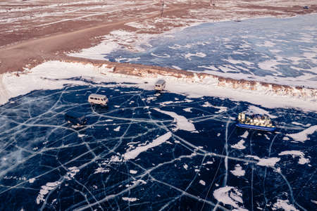 Travel winter lake Baikal, clear ice surface with mountains and touristsの写真素材
